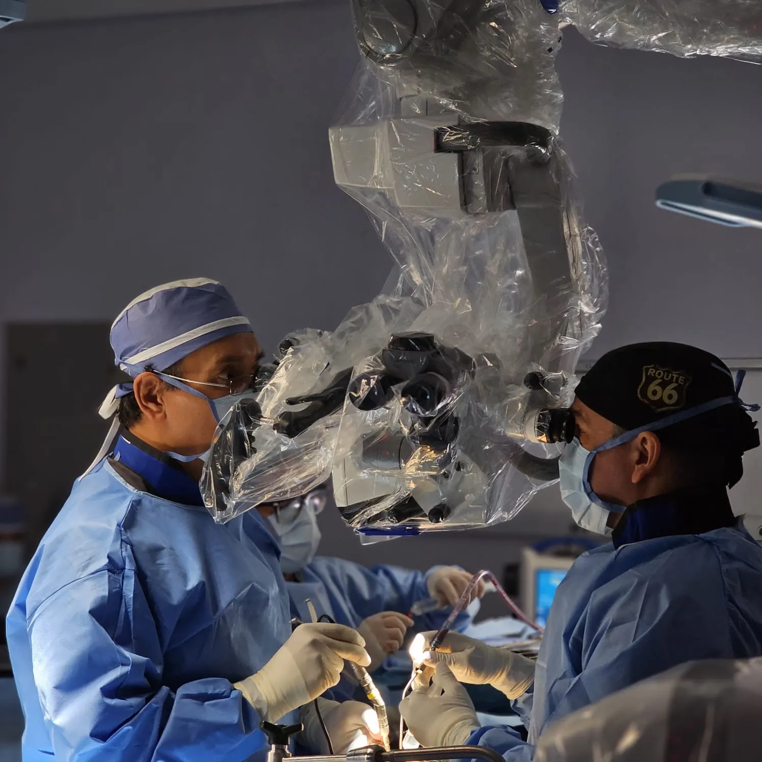 Dr. Carrillo operating with a surgical microscope alongside his assistant