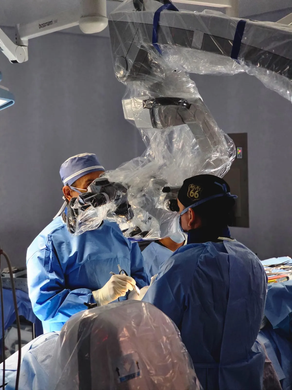 El Dr. Carrillo y su ayudante frente al microscopio quirúrgico